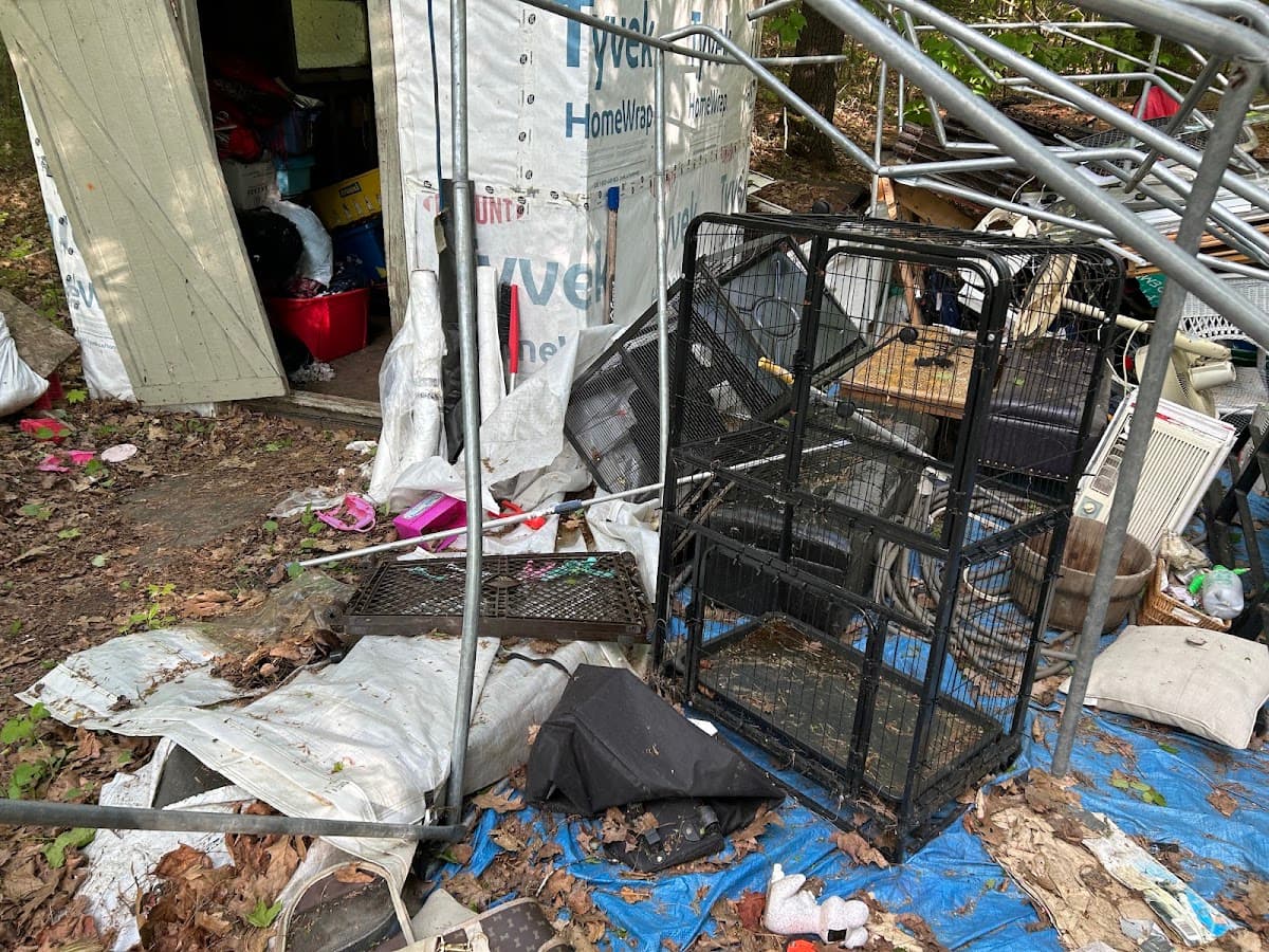 Old cages and household items scattered beside a shed before cleanout