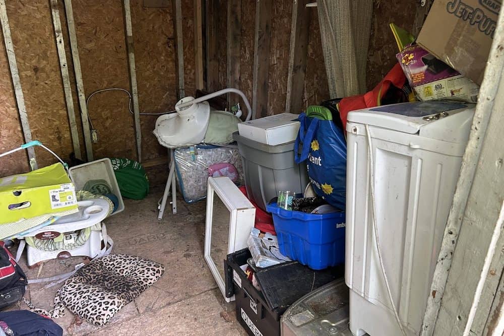 Un cabanon rempli d'une vieille laveuse, de chaises et de boîtes avant le vidage