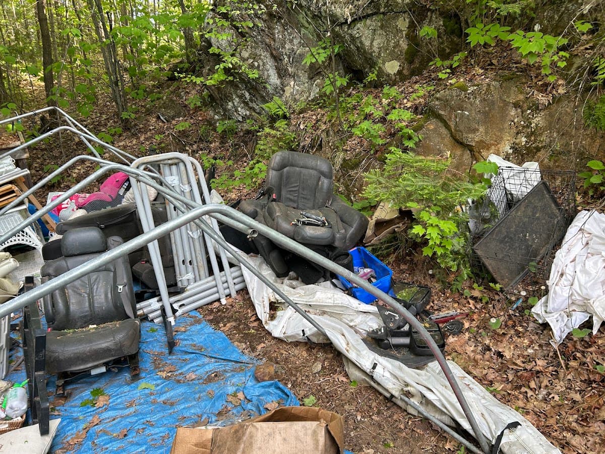 A backyard junk pile with old car seats and metal frames before removal