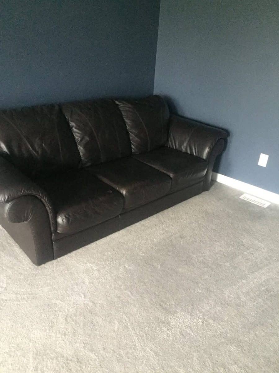 Un vieux divan de cuir noir laissé dans une pièce vide