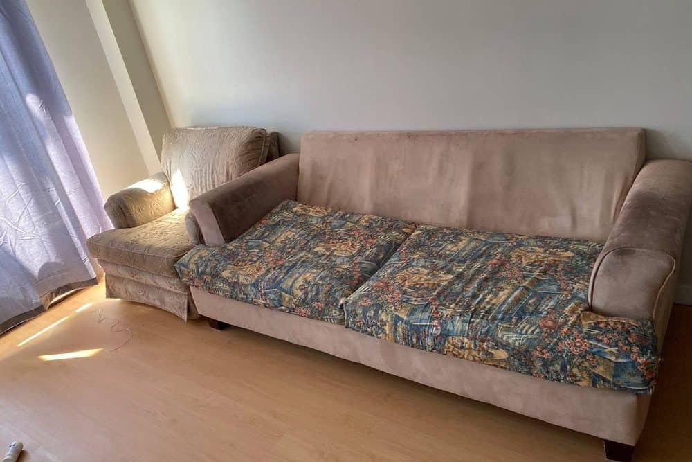 Un divan usé et son fauteuil assorti prêts à être sortis d'un salon