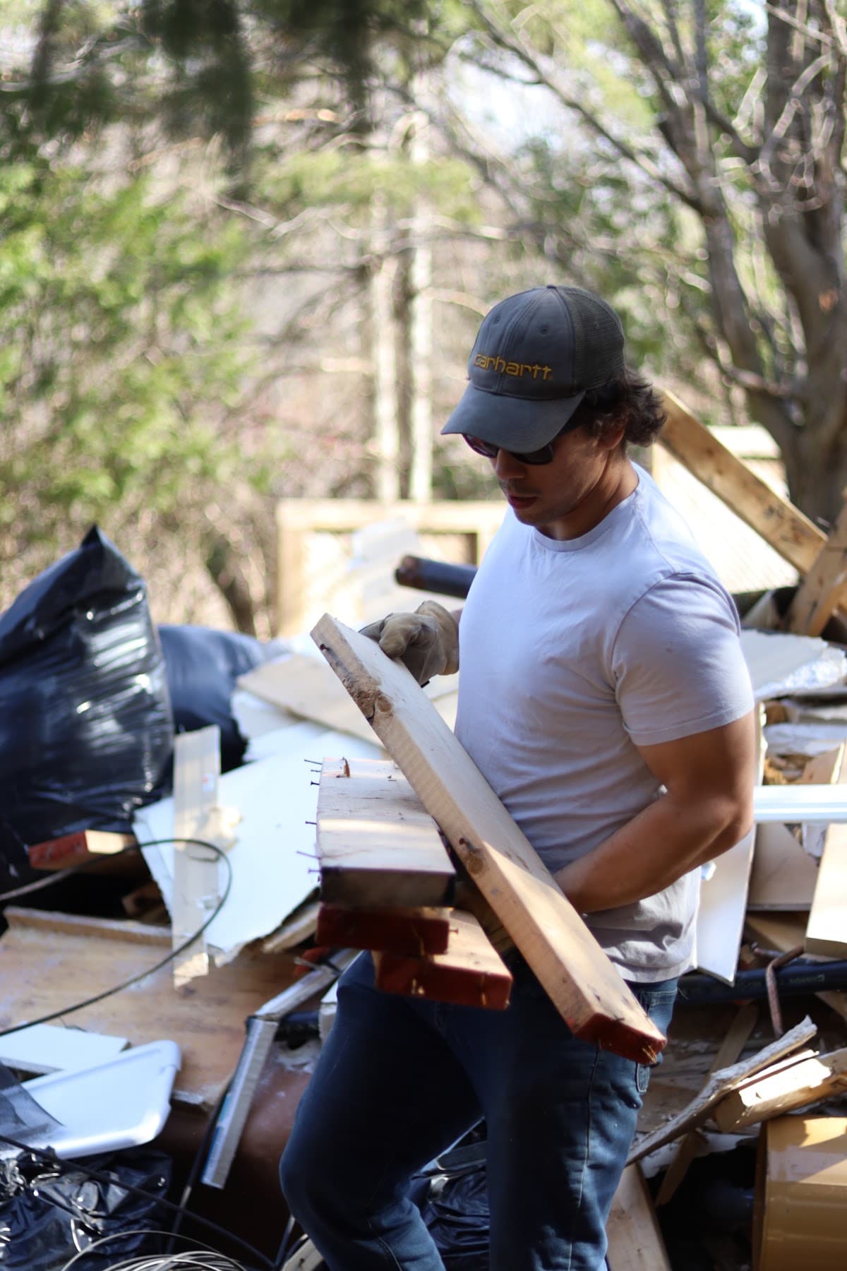 Crew member carrying lumber away from a demolition pile