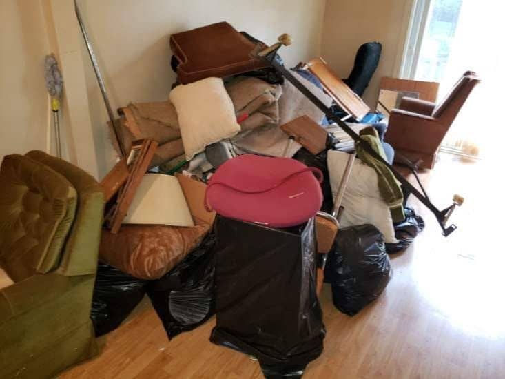 Une pièce remplie mur à mur de vieux meubles, de matelas et de sacs